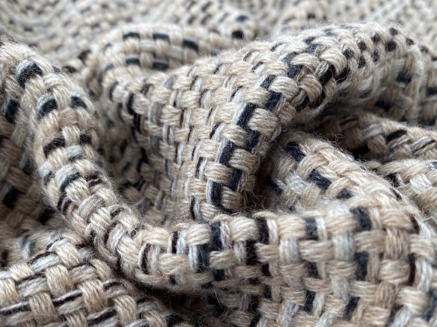 Nahaufnahme des groben Korbgewebes einer Kaschmirdecke in Beige und Schwarz